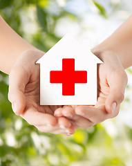 Image showing hands holding paper house with red cross