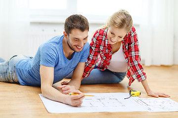 Image showing smiling couple looking at blueprint at home