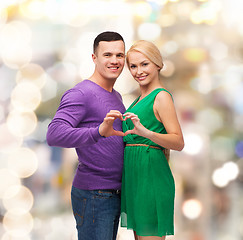 Image showing smiling couple showing heart with hands