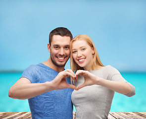 Image showing smiling couple showing heart with hands