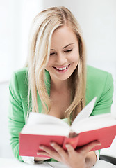 Image showing smiling young woman reading book at school