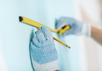 Image showing closeup of male in gloves measuring wall with tape