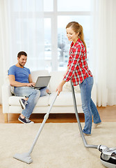 Image showing smiling woman with hoover and man with laptop