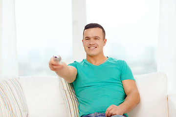 Image showing smiling man with tv remote control at home