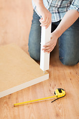 Image showing close up of male hands assemblying legs to table