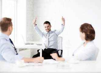 Image showing happy businessman showing thumbs up in office