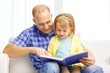 Image showing smiling father and daughter with book at home