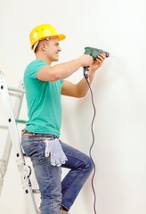 Image showing man with electric drill making hole in wall