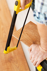 Image showing close up of male hands cutting parquet floor board