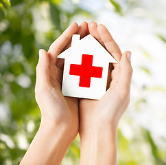 Image showing hands holding paper house with red cross