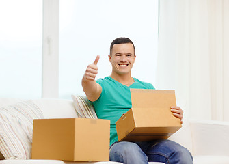 Image showing man with cardboard boxes at home showing thumbs up