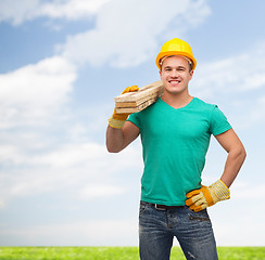 Image showing smiling manual worker in helmet with wooden boards