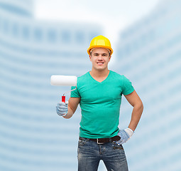 Image showing smiling manual worker in helmet with paint roller