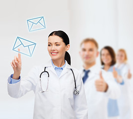 Image showing smiling female doctor pointing to envelope