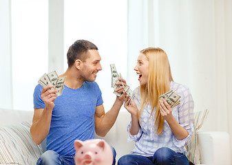 Image showing couple with money and piggybank ot table at home