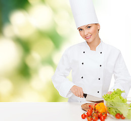 Image showing smiling female chef chopping vagetables