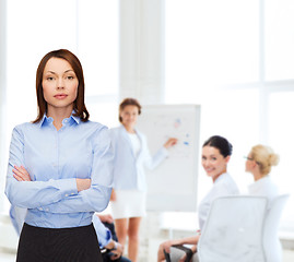 Image showing smiling businesswoman with crossed arms at office