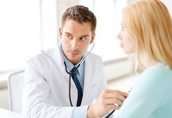 Image showing doctor with stethoscope listening to the patient