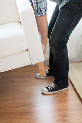 Image showing close up of male lifting up sofa to move