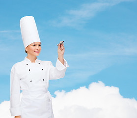 Image showing smiling female chef writing something on air