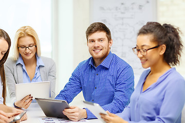 Image showing smiling team with table pc and papers working