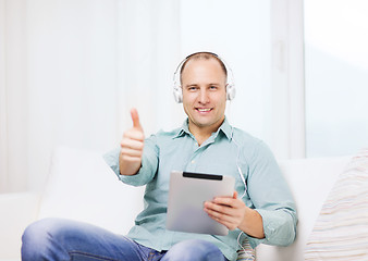 Image showing smiling man with tablet pc and headphones at home