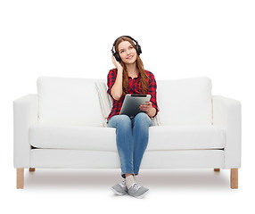 Image showing girl sitting on sofa with headphones and tablet pc