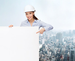 Image showing businesswoman in helmet pointing finger to board