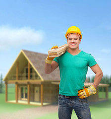 Image showing smiling manual worker in helmet with wooden boards