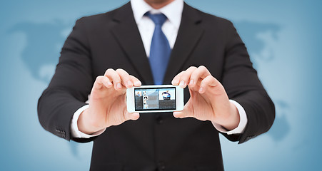 Image showing businessman with smartphone and news on screen