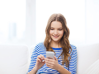 Image showing smiling teenage girl with smartphone at home