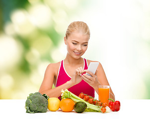 Image showing woman with vegetables pointing at smartphone