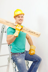 Image showing smiling manual worker in helmet with wooden boards
