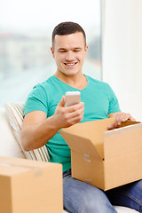 Image showing opening cardboard box and taking out smartphone