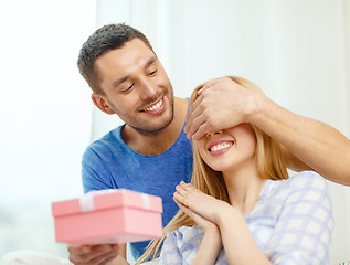 Image showing smiling man surprises his girlfriend with present