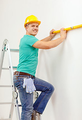 Image showing smiling man building using spirit level to measure