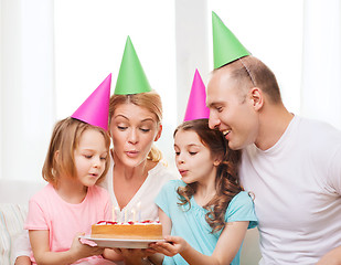 Image showing smiling family with two kids in hats with cake