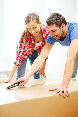 Image showing smiling couple opening big cardboard box