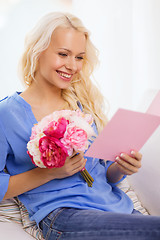 Image showing smiling woman with card and bouquet of flowers