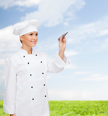 Image showing smiling female chef writing something on air