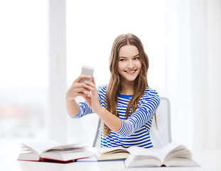 Image showing smiling student girl with smartphone and books