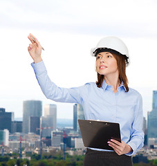 Image showing smiling businesswoman in helmet with clipboard