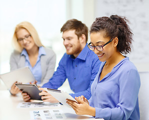 Image showing smiling team with table pc and papers working