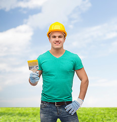 Image showing smiling manual worker in helmet with paintbrush