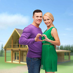 Image showing smiling couple showing heart with hands