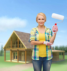 Image showing smiling woman in gloves with paint roller