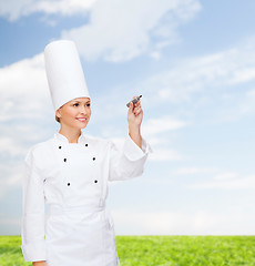 Image showing smiling female chef writing something on air