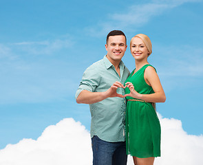 Image showing smiling couple showing heart with hands