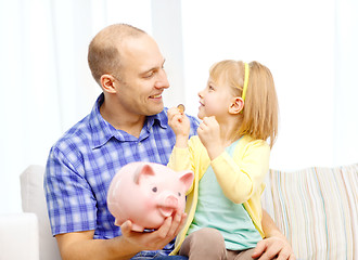 Image showing happy father and daughter with big piggy bank