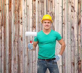 Image showing smiling manual worker in helmet with paint roller